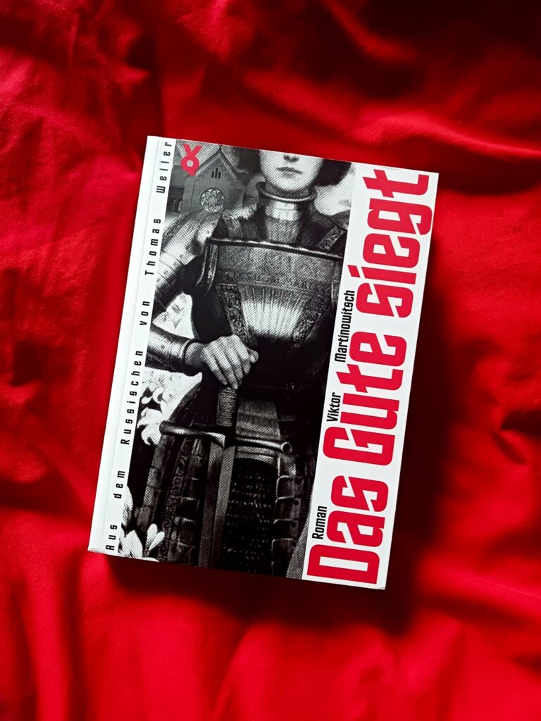 Foto des Buches, auf dessen Schwarz-Weiß-Cover Teile einer gerüsteten Frau (Jeanne d’Arc) zu sehen sind, die mit der rechten Hand ein vor sich aufrecht hingestelltes Schwert hält; oberhalb der Wangenknochen und etwa ab den Knien nach unten ist das Bild beschnitten. Hinter ihr sind weiße Lilien und ein Kirchenbau mit einer Fensterrosette zu sehen. Das Buch liegt auf einem roten, Falten werfenden Stoff, der die Farbe der Schrift auf dem Cover aufnimmt. Übersetzungslektorat